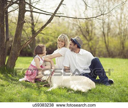 Stock Photo - Family sitting in park with dog. Fotosearch