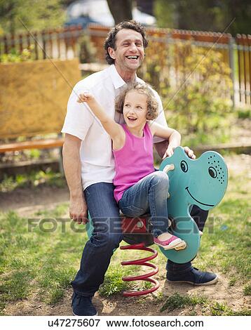 Stock Photo - Father and daughter on playground spring rider. Fotosearch