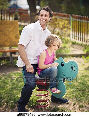Stock Photograph - Father and daughter on playground spring rider. Fotosearch