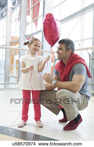Father gives young daughter heart shaped balloon View Large Photo Image Picture - Father gives young daughter heart shaped balloon. Fotosearch