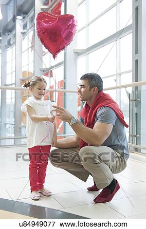 Stock Photo - Father gives young daughter heart shaped balloon. Fotosearch