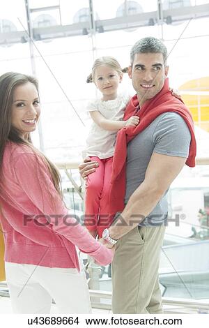 Father holding young daughter up at waist height and holding hands with mother View Large Photo Image Picture - Father holding young daughter up at waist height and holding hands with mother. Fotosearch