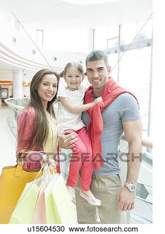 Father holding young girl posing with mother in shopping mall View Large Photo Image Stock Image - Father holding young girl posing with mother in shopping mall. Fotosearch