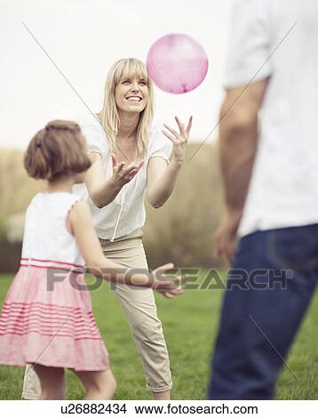Picture - Father mother and daughter throwing ball to each other in the park. Fotosearch