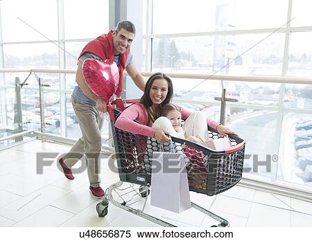 Father pushing mother and young daughter in shopping trolley View Large Photo Image Stock Photography - Father pushing mother and young daughter in shopping trolley. Fotosearch