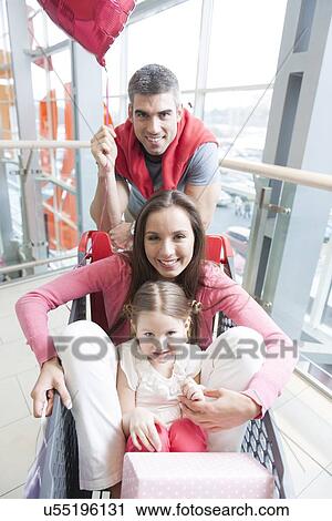 Front on view of mother and young daughter in trolley with father pushing View Large Photo Image Stock Image - Front on view of mother and young daughter in trolley with father pushing. Fotosearch