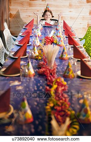 Happy young girl at her dinner party table wearing party hat View Large Photo Image Stock Image - Happy young girl at her dinner party table wearing party hat. Fotosearch