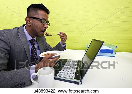 Indian businessman eating at his desk View Large Photo Image Stock Image - Indian businessman eating at his desk. Fotosearch
