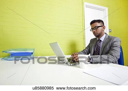Stock Photography - Indian businessman working at his desk. Fotosearch