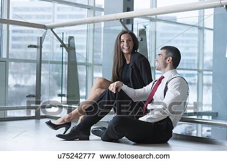 Stock Photo - Male and female coworkers sitting and joking together. Fotosearch