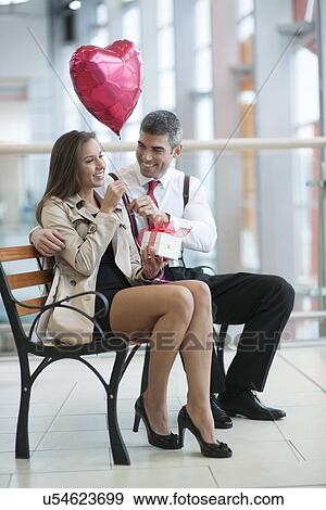 Man gives woman gift and heart shaped balloon View Large Photo Image Stock Photo - Man gives woman gift and heart shaped balloon. Fotosearch