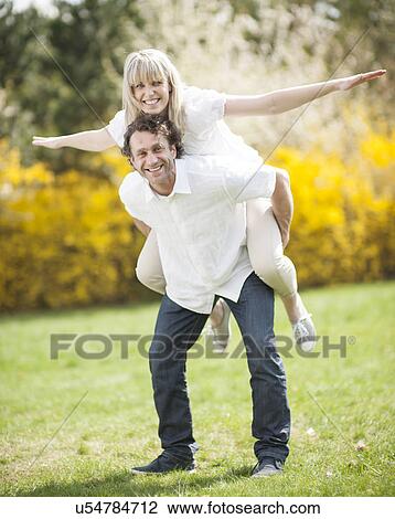 Man piggybacking woman in park View Large Photo Image Stock Image - Man piggybacking woman in park. Fotosearch