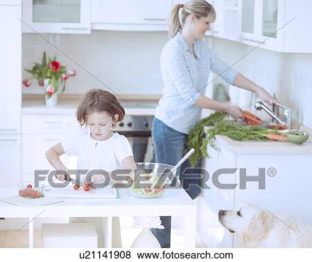 Stock Photo - Mother and Daughter (8-9) preparing healthy meal in kitchen. Fotosearch