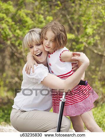 Mother and daughter hug in park with scooter View Large Photo Image Stock Image - Mother and daughter hug in park with scooter. Fotosearch