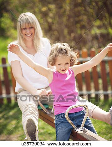 Picture - Mother and daughter ride seesaw together. Fotosearch