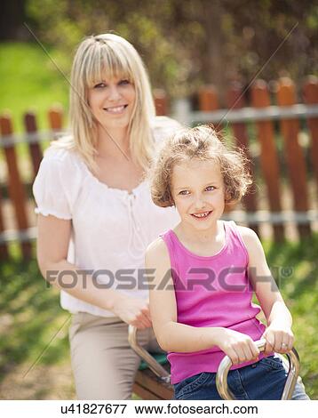 Mother and daughter ride seesaw together View Large Photo Image Stock Photo - Mother and daughter ride seesaw together. Fotosearch