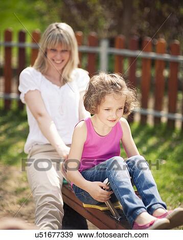Mother and daughter ride seesaw together View Large Photo Image Stock Photo - Mother and daughter ride seesaw together. Fotosearch