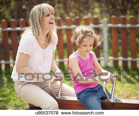 Mother and daughter ride seesaw together View Large Photo Image Stock Photo - Mother and daughter ride seesaw together. Fotosearch
