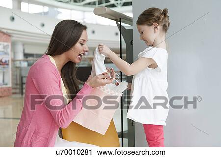 Mother giving daughter gift from paper shopping bag View Large Photo Image Stock Image - Mother giving daughter gift from paper shopping bag. Fotosearch