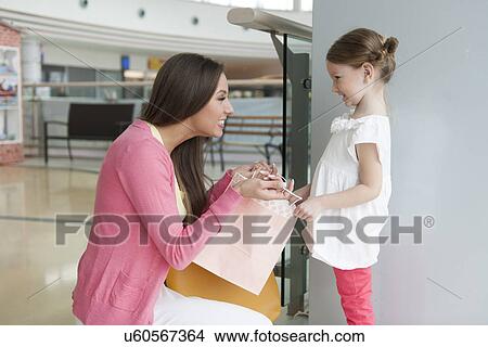 Mother giving daughter paper shopping bag View Large Photo Image Picture - Mother giving daughter paper shopping bag. Fotosearch
