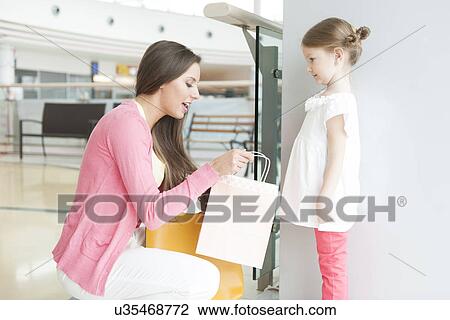 Mother giving daughter paper shopping bag View Large Photo Image Stock Image - Mother giving daughter paper shopping bag. Fotosearch