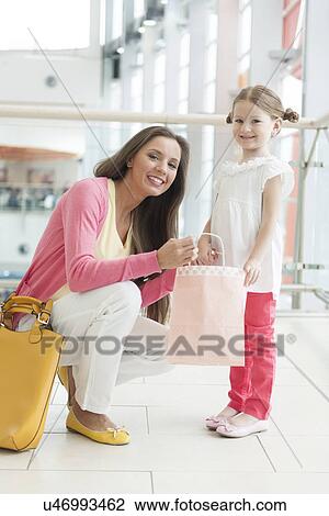 Mother giving daughter paper shopping bag View Large Photo Image Stock Image - Mother giving daughter paper shopping bag. Fotosearch