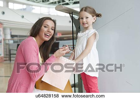 Stock Photo - Mother giving daughter paper shopping bag. Fotosearch