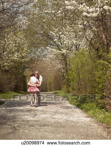 Mother hugging young girl in distance in a park View Large Photo Image Picture - Mother hugging young girl in distance in a park. Fotosearch