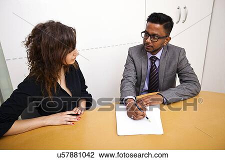 Multi-ethnic work colleagues signing paperwork on a table View Large Photo Image Stock Image - Multi-ethnic work colleagues signing paperwork on a table. Fotosearch
