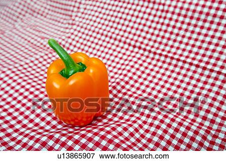 Stock Photo - Orange Bell Pepper against red and white chequered cloth. Fotosearch