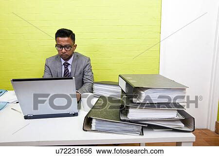 Portrait of Indian Businessman working on his laptop computer at his desk View Large Photo Image Stock Photograph - Portrait of Indian Businessman working on his laptop computer at his desk. Fotosearch