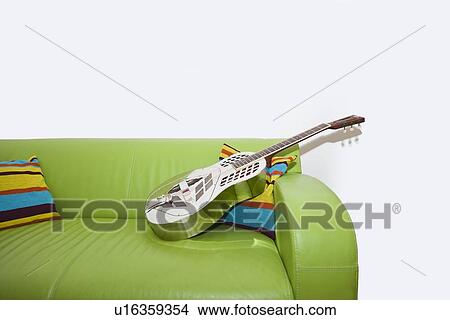 Picture - Resonator Guitar on a Green Sofa. Fotosearch