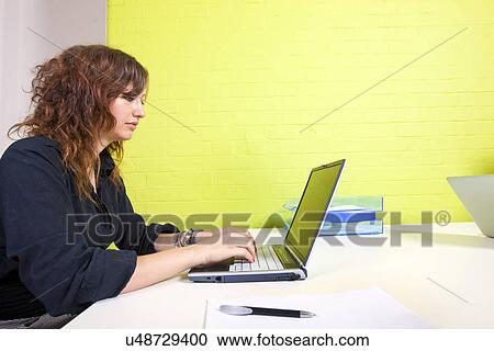 Side view of woman working at her computer View Large Photo Image Stock Image - Side view of woman working at her computer. Fotosearch