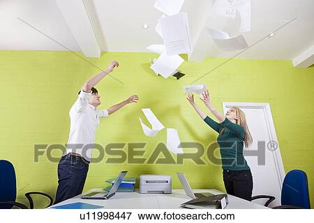 Side view of young businesspeople throwing documents in office View Large Photo Image Stock Photo - Side view of young businesspeople throwing documents in office. Fotosearch