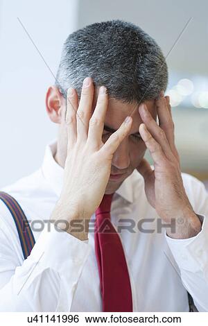 Stock Photograph - Stressed out businessman holding hands to face. Fotosearch