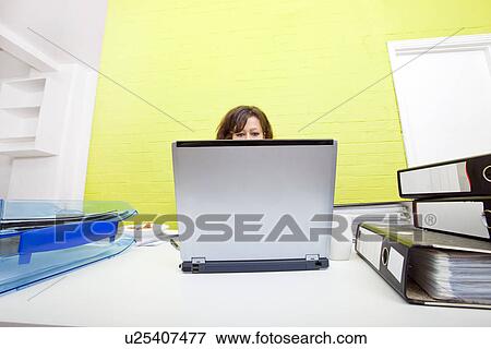 Stock Photo - Womans head poking out over top of laptop. Fotosearch
