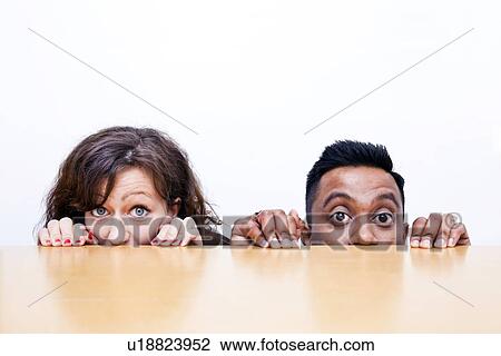 Work colleagues peeking over edge of table View Large Photo Image Stock Image - Work colleagues peeking over edge of table. Fotosearch