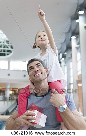 Stock Photograph - Young daughter points and sits on fathers shoulders. Fotosearch