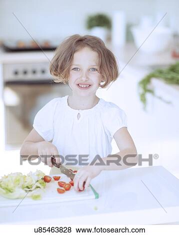 Young girl chopping tomatoes and making a salad in the kitchen View Large Photo Image Stock Photo - Young girl chopping tomatoes and making a salad in the kitchen. Fotosearch