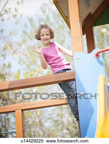 Stock Photography - Young girl climbing on childrens playground and waving at camera. Fotosearch