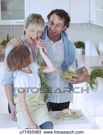 Young girl eating carrot with parents View Large Photo Image Stock Image - Young girl eating carrot with parents. Fotosearch