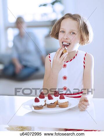 Stock Photography - Young girl eating cup cake. Fotosearch