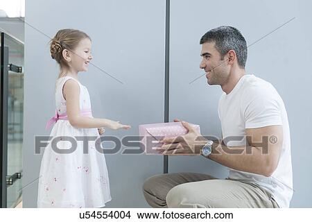 Young girl handing present to her father View Large Photo Image Picture - Young girl handing present to her father. Fotosearch