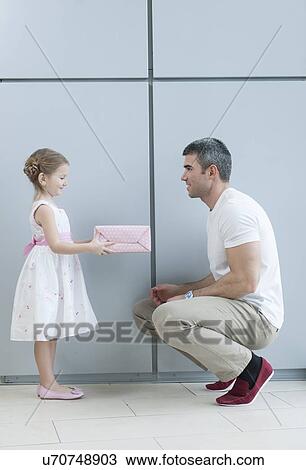 Young girl handing present to her father View Large Photo Image Stock Image - Young girl handing present to her father. Fotosearch