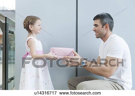 Young girl handing present to her father View Large Photo Image Stock Photo - Young girl handing present to her father. Fotosearch