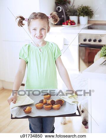 Young girl holding baking tray in kitchen View Large Photo Image Stock Image - Young girl holding baking tray in kitchen. Fotosearch