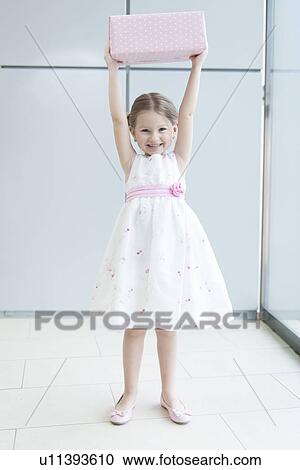 Young girl holding gift wrapped box above her head View Large Photo Image Stock Image - Young girl holding gift wrapped box above her head. Fotosearch