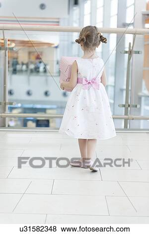 Young girl holding gift wrapped boxes walking away from camera View Large Photo Image Stock Photo - Young girl holding gift wrapped boxes walking away from camera. Fotosearch