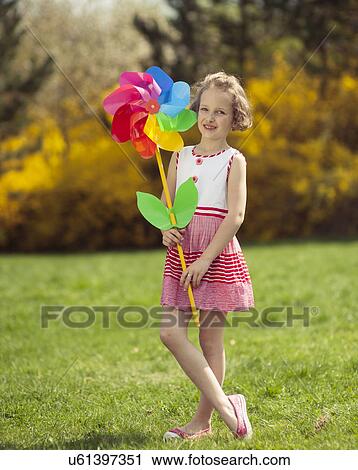 Young girl holding large Flower shaped wind wheel View Large Photo Image Stock Image - Young girl holding large Flower shaped wind wheel. Fotosearch