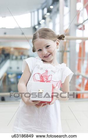 Young girl holding present wrapped in big red bow View Large Photo Image Stock Photo - Young girl holding present wrapped in big red bow. Fotosearch